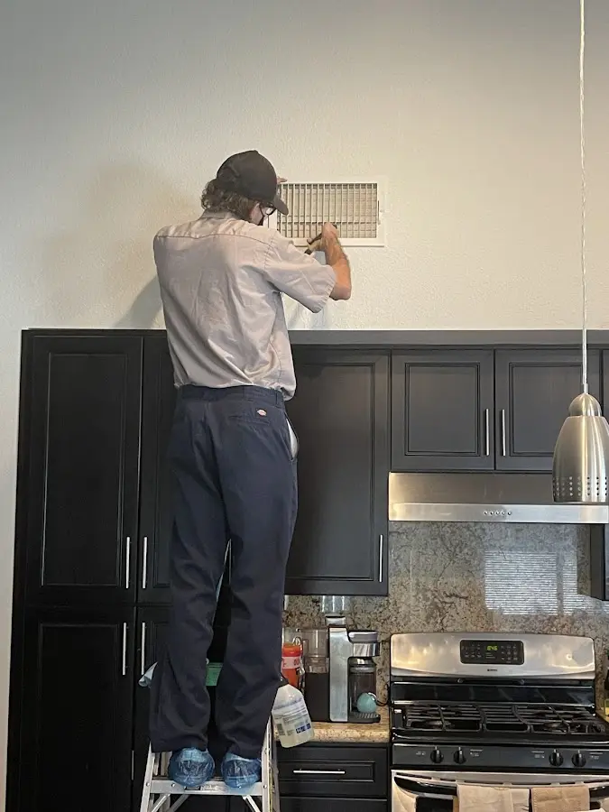 Technician inspecting an air vent during HVAC service in Long Beach